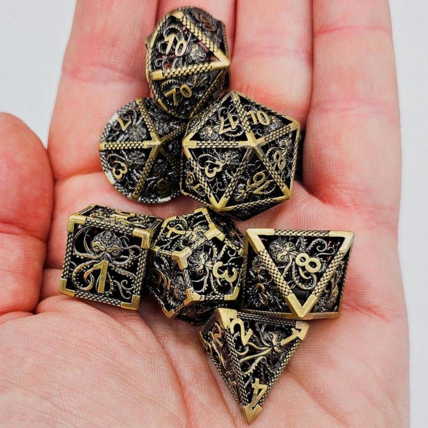 Ancient Gold Hollow Metal Cthulhu DND Dice Set in the palm of someones hand.