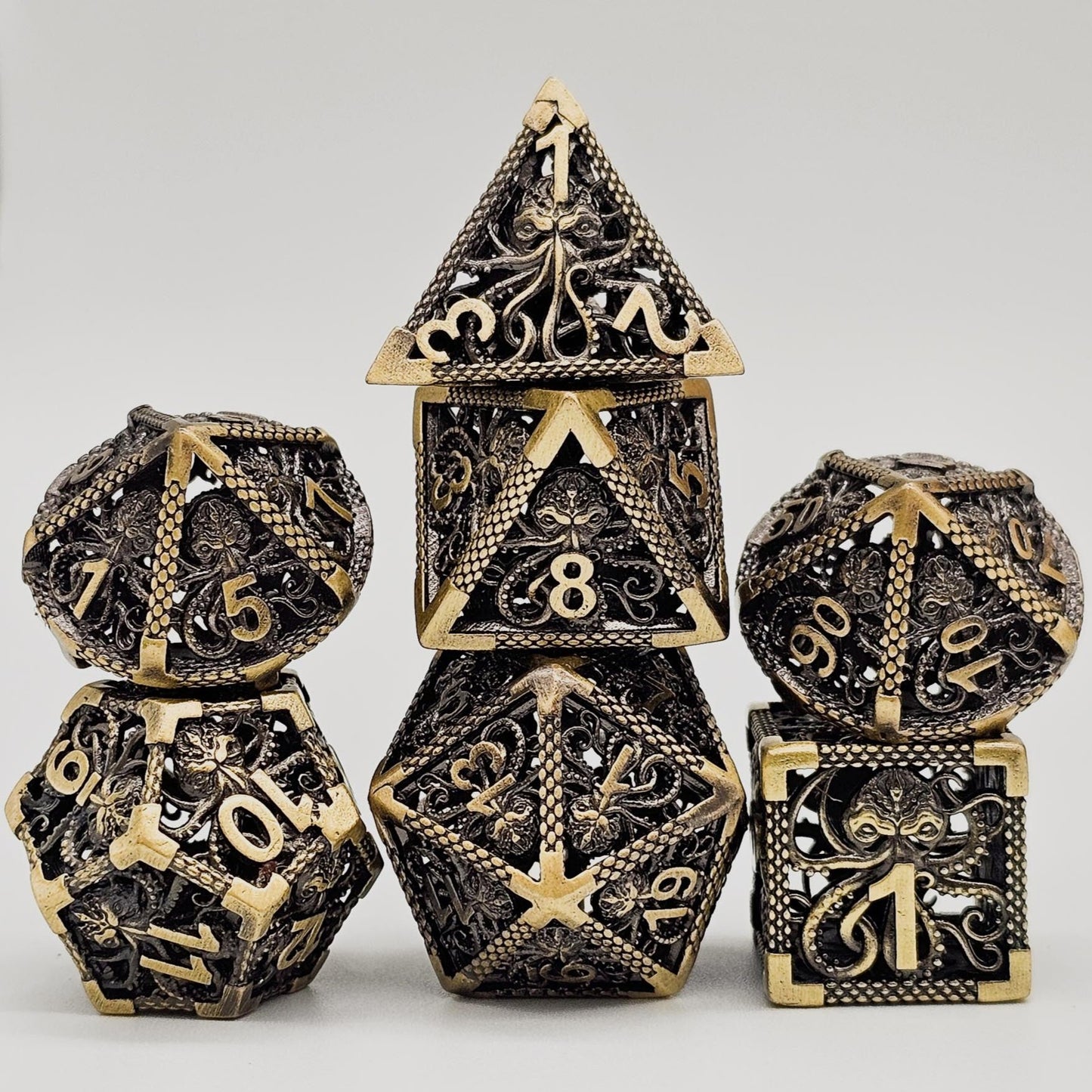 Ancient Gold Hollow Metal Cthulhu DND Dice Set stacked up like a pyramid.