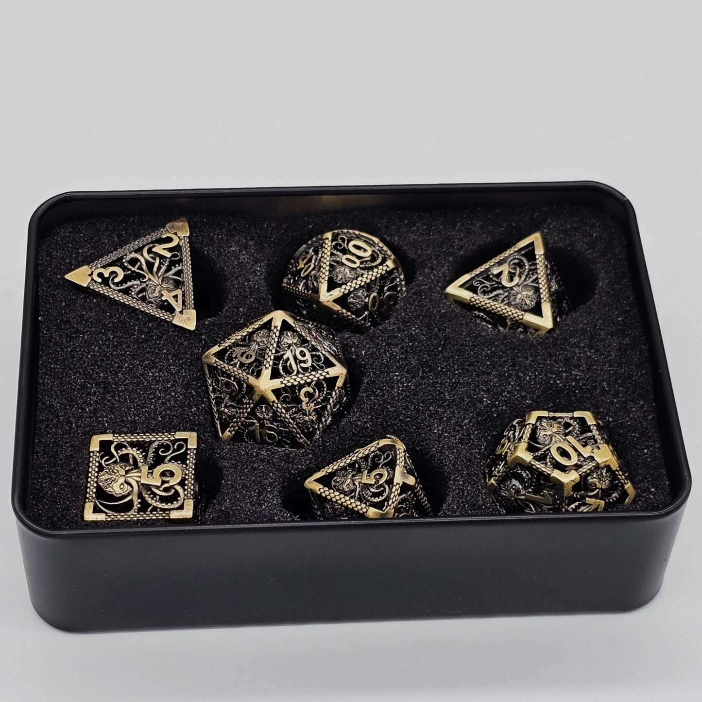 Ancient Gold Hollow Metal Cthulhu DND Dice Set inside a black metal container.
