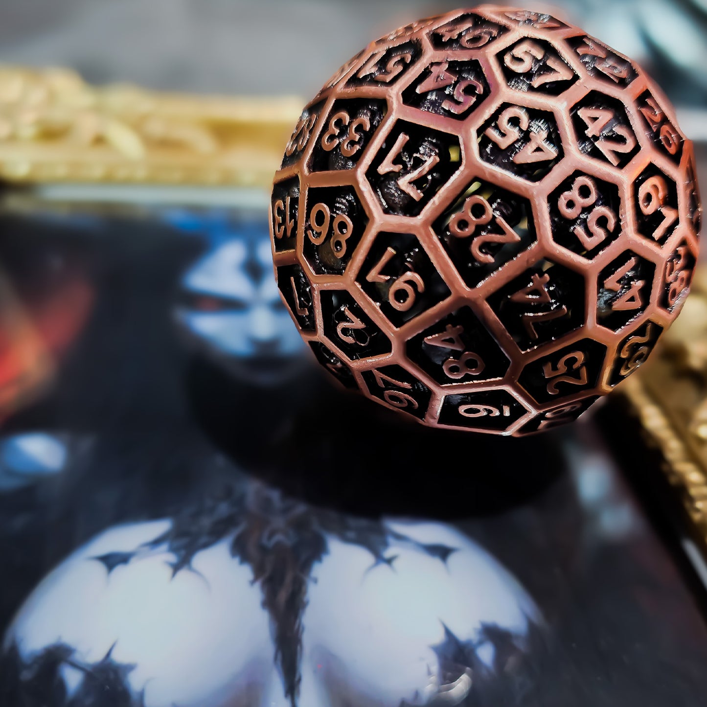 Red Copper Hollow Metal D100 DND Dice on top of a picture with a golden frame and a picture of a large breasted female devil.