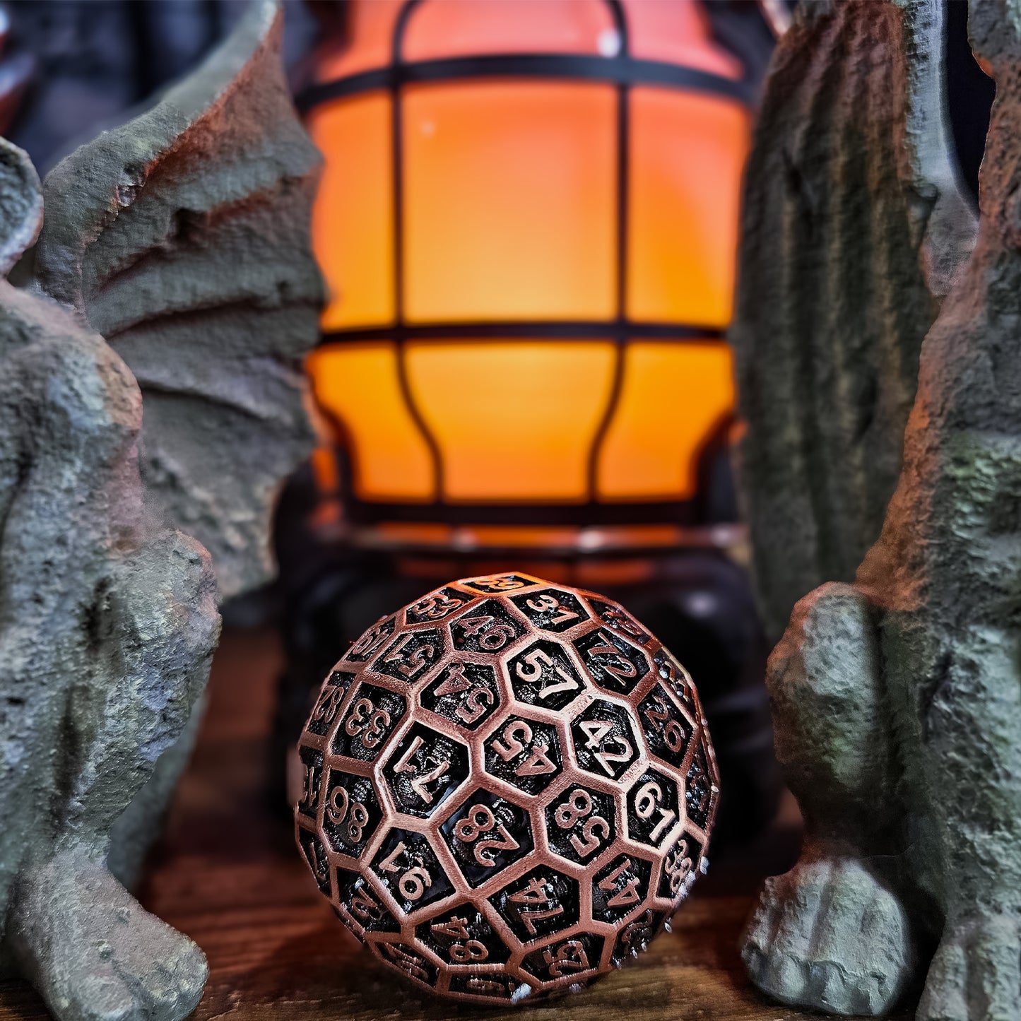 Red Copper Hollow Metal D100 DND Dice in between two gargoyle statues with an orange flickering lantern behind them.
