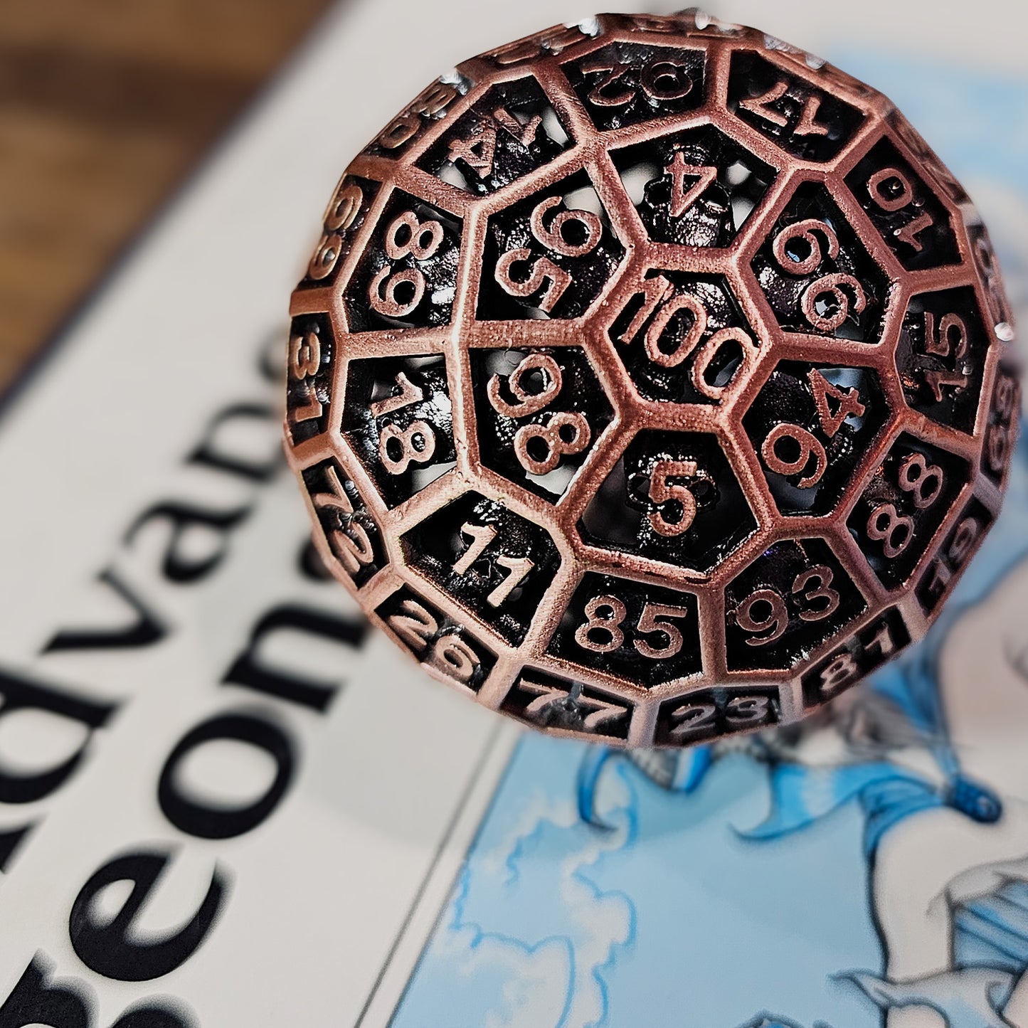 Red Copper Hollow Metal D100 DND Dice on top of a white and blue Dungeons and Dragons Advanced manual.