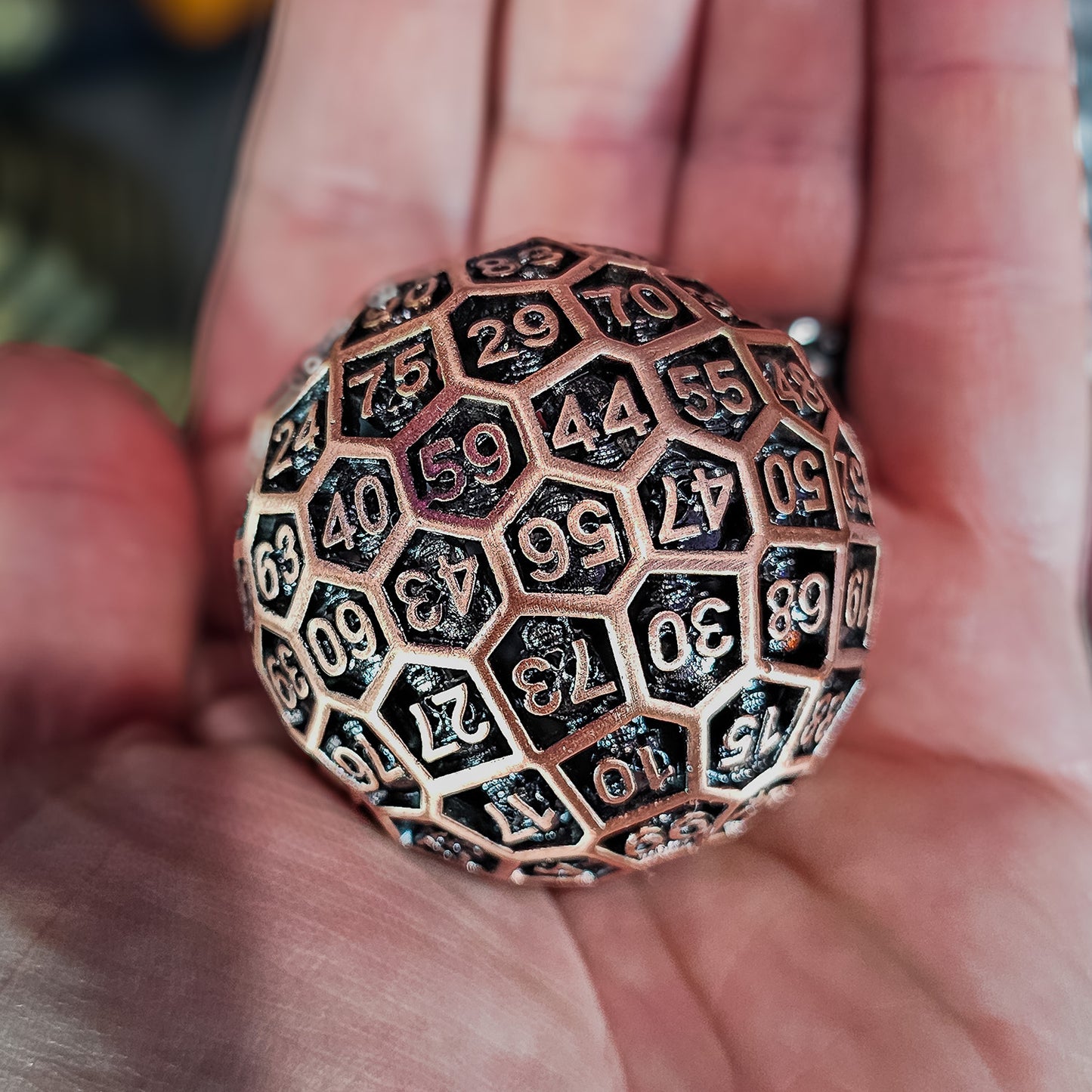 Red Copper Hollow Metal D100 DND Dice in the palm of a person hand