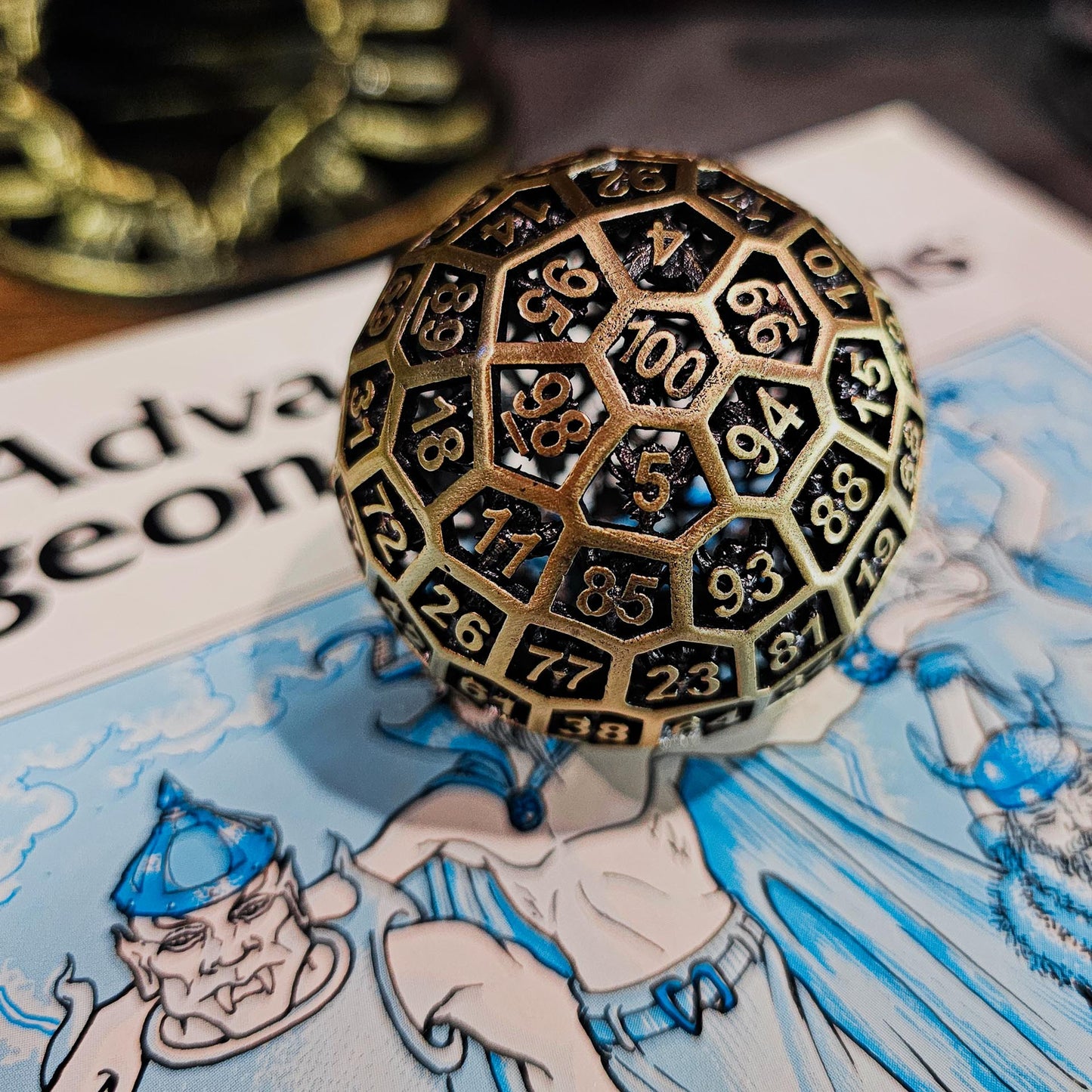 Hollow Metal Ancient Gold D100 DND Dice on top of a white and blue Advanced Dungeons and Dragons manual.