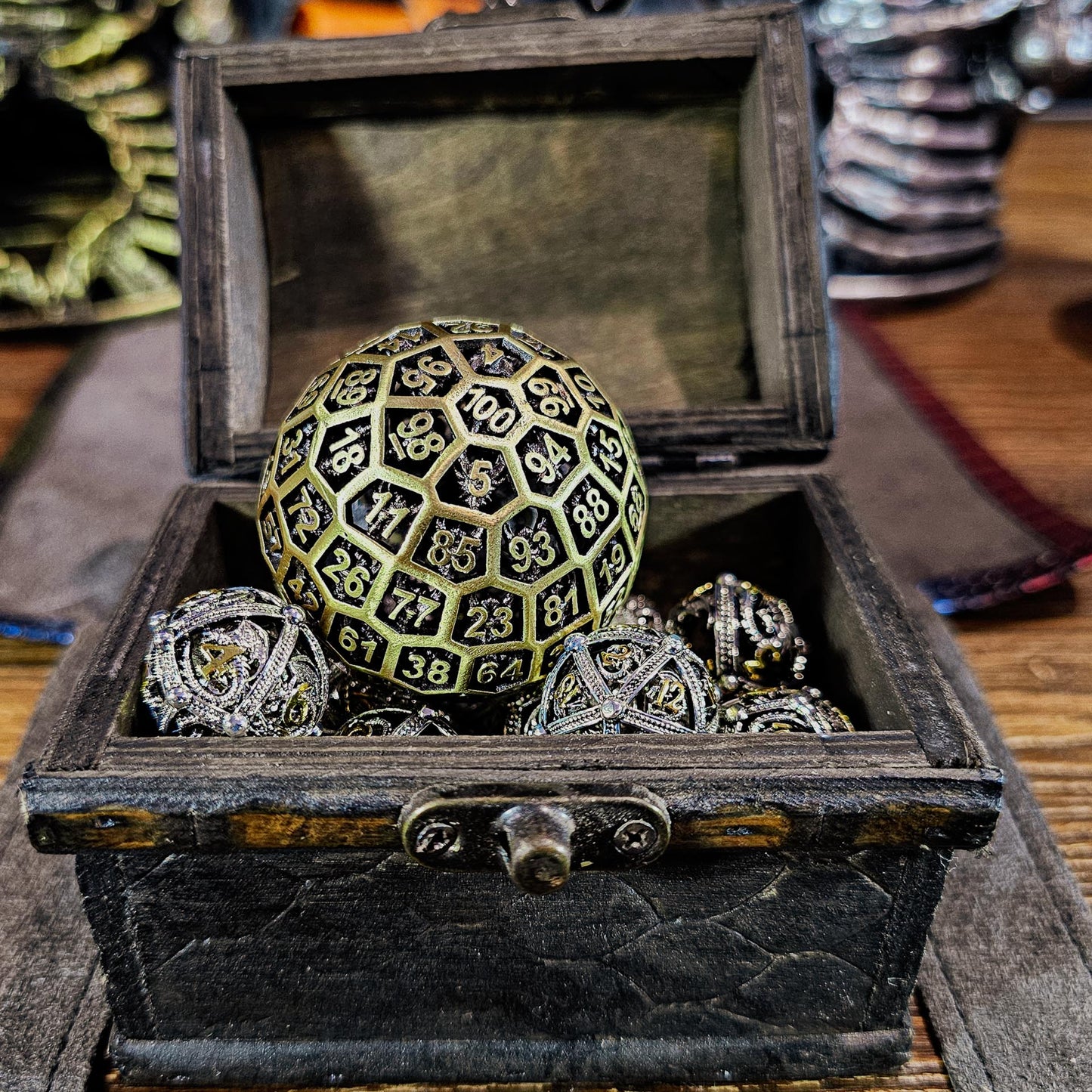 Hollow Metal Ancient Gold D100 DND Dice inside a treasure chest that has shiny silver and gold hollow metal orb shaped DND Dice