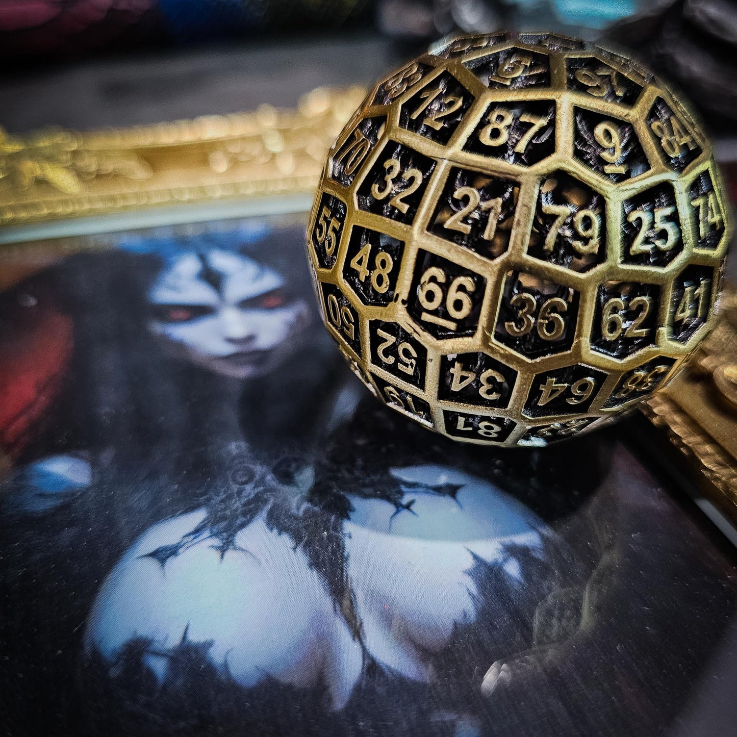 Hollow Metal Ancient Gold D100 DND Dice on a golden framed picture of a large breasted female devil.