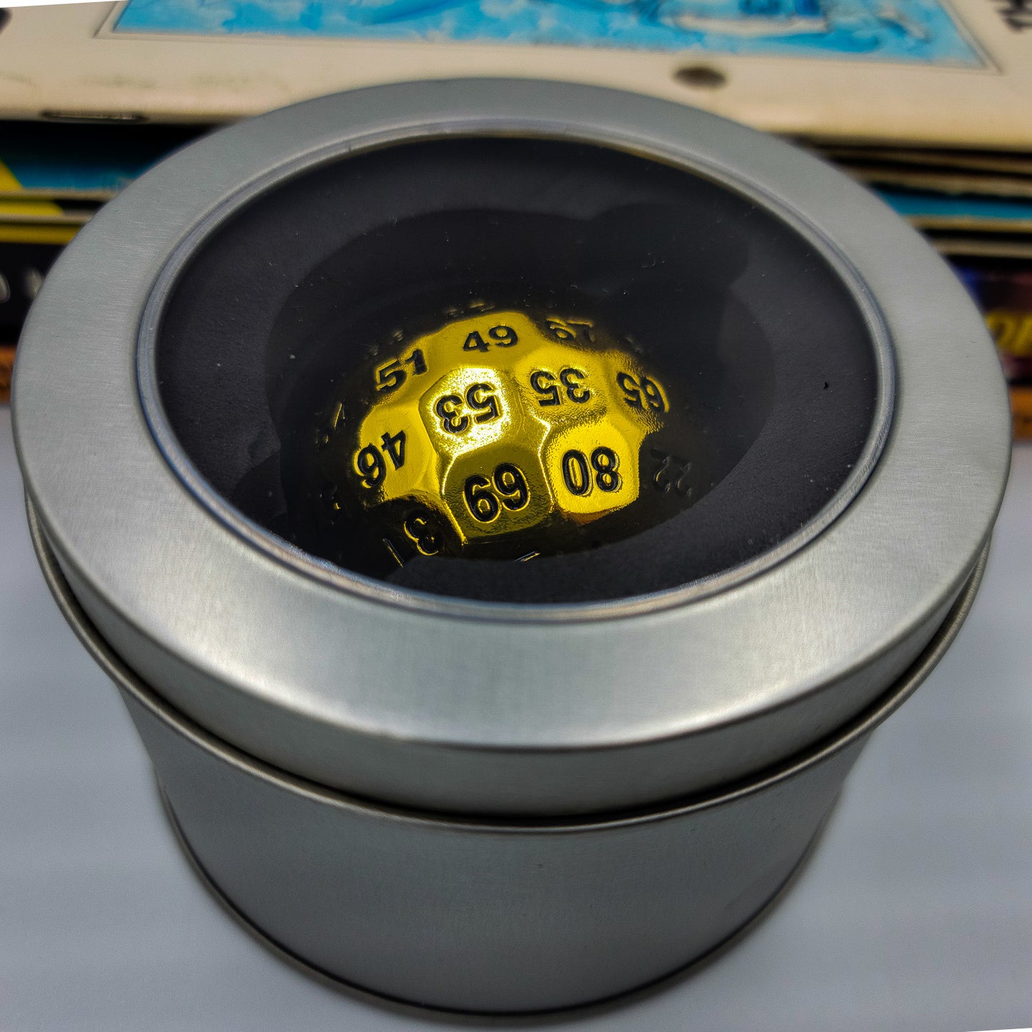 Metal Shiny Gold D100 DND Dice inside a silver metal container with a see through plastic window on the lid.