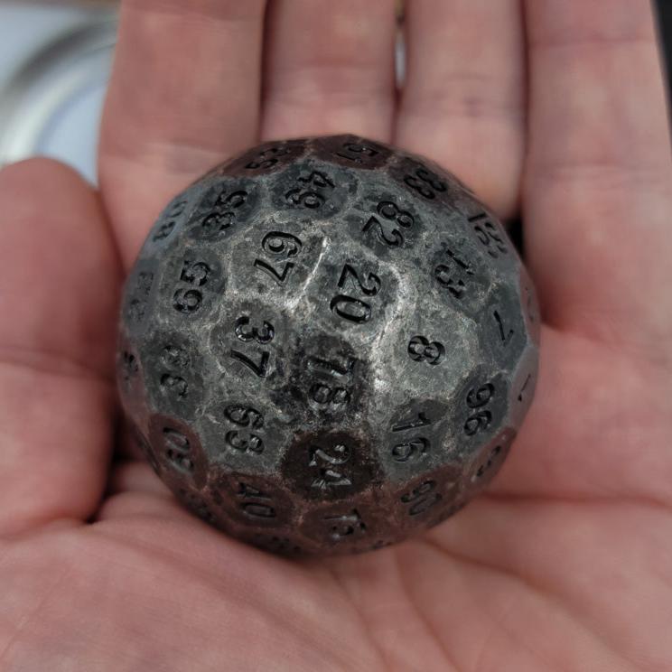 Metal Silver D100 DND Dice in the palm of someones hand.