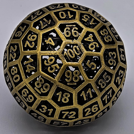 Hollow Metal Ancient Gold D100 DND Dice in front of a white mechanical keyboard that is standing up with its keys facing the camera.