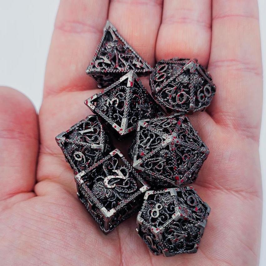 Silver Hollow Metal DND Dice with blood spatters on a cthulhu etched theme in the palm of a persons hand.