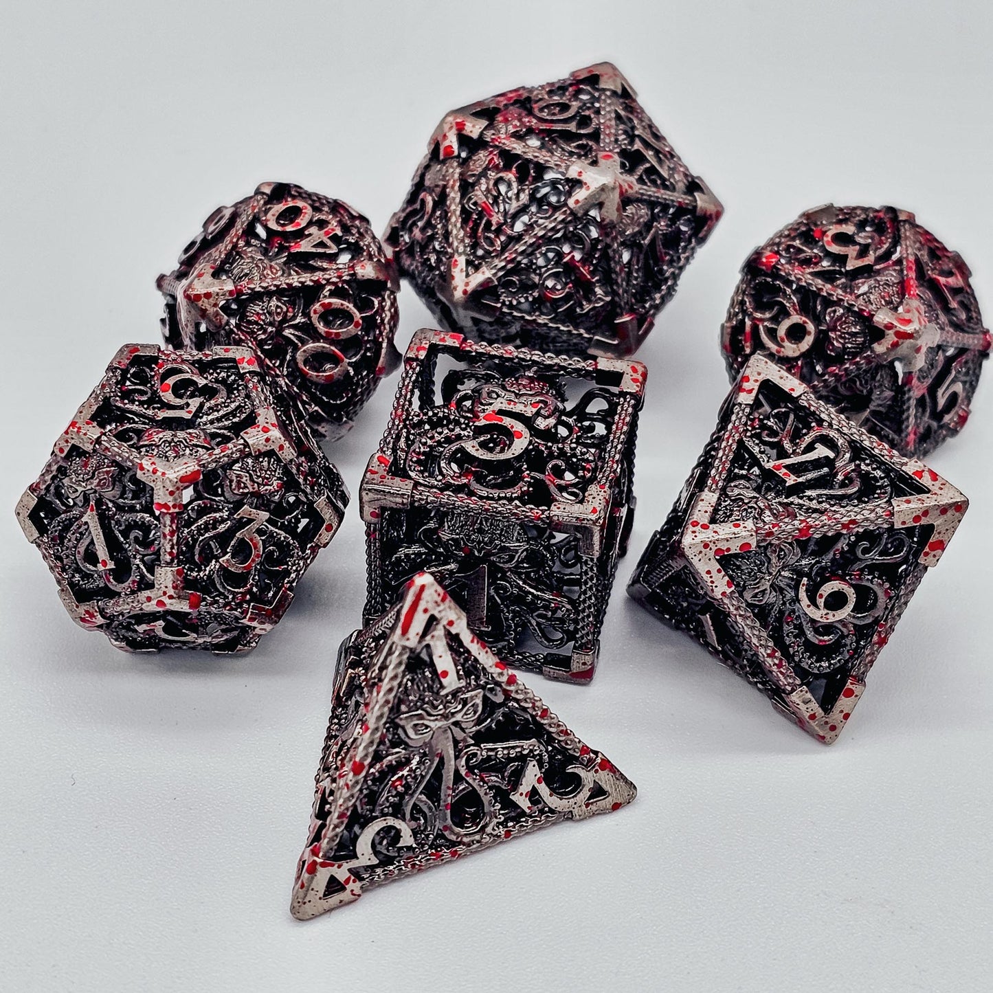 Silver with blood spatters hollow metal DND dice with cthulhu etches theme.