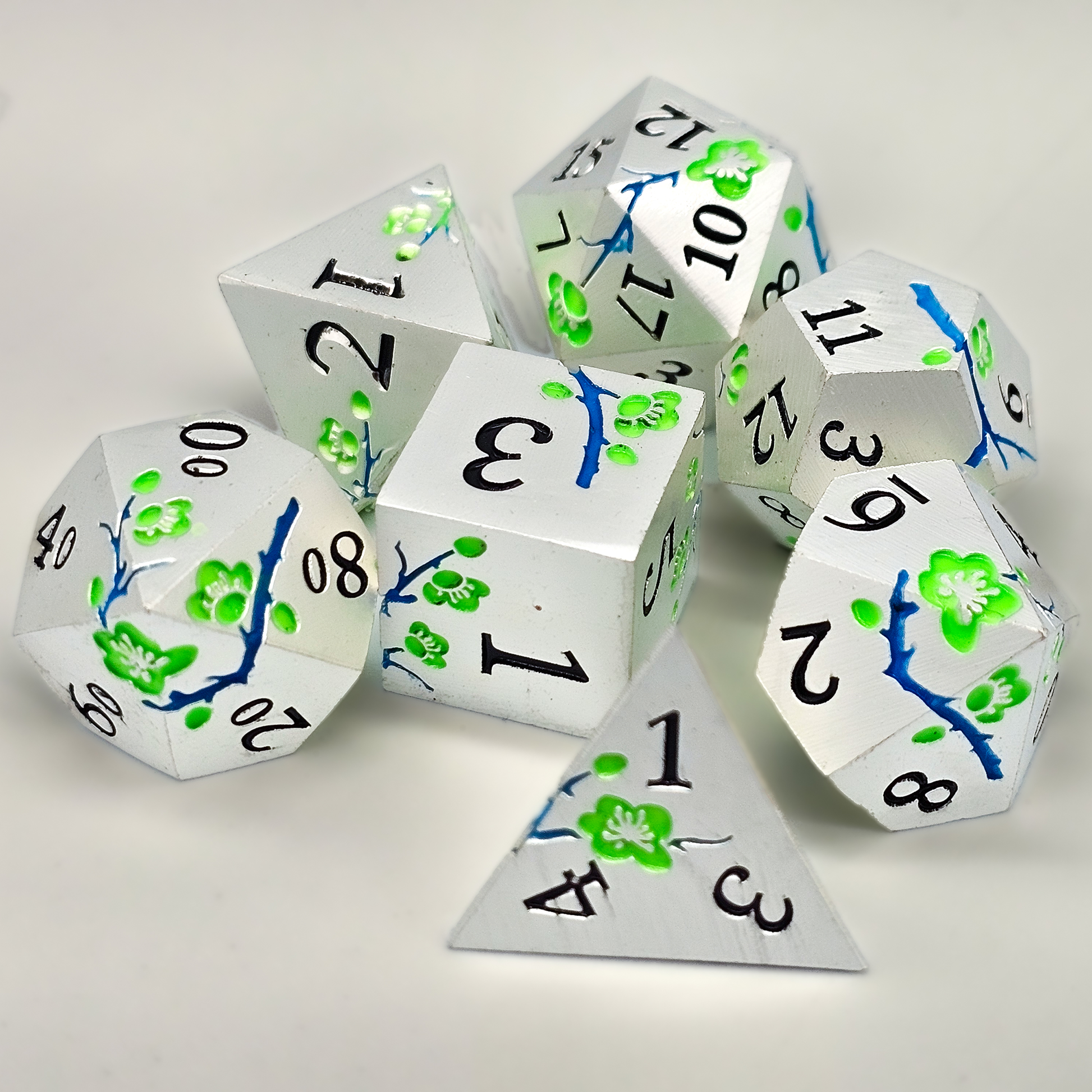 Silver solid metal DND Dice with green japanese plum blossoms and blue twigs etched into the sides