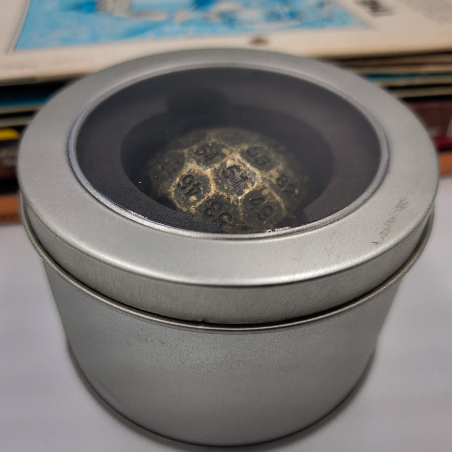 Solid Metal Antique Gold D100 DND Dice inside a silver metal container with plastic see through lid.